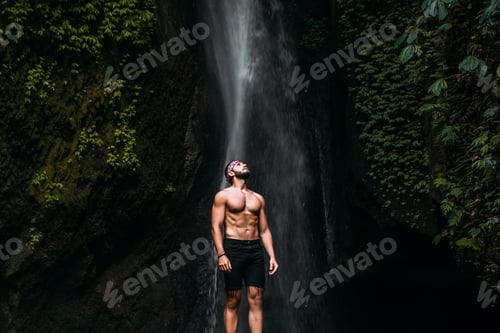 Preview: A man of athletic build at the waterfall. A man travels the world. Man at the waterfall
