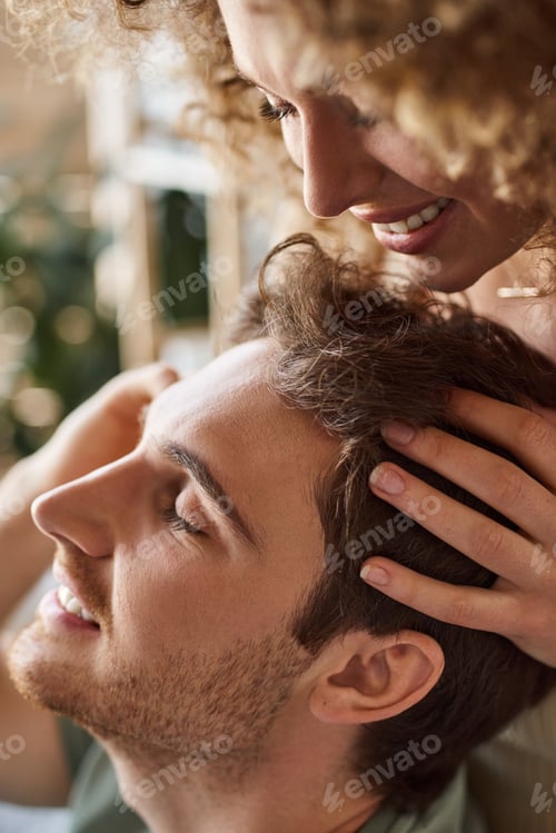 Preview: Closeup of curly young woman gently massaging boyfriends head smiling together
