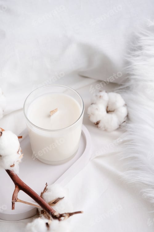 Preview: Soy wax aroma candle in white jar on bed with cotton branch. Candle mockup design