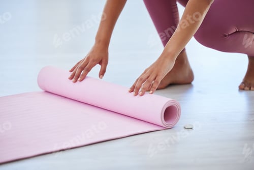 Preview: Closeup shot of an unrecognisable woman rolling an exercise mat on the floor in a yoga studio
