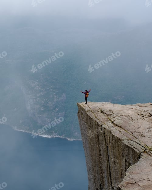 Preview: Daring Adventurer Standing on Pulpit Rock Overlooking Norway's Majestic Fjords, Preikestolen Norway