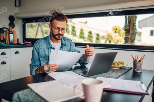 Preview: Young business man working at home with laptop and papers on desk