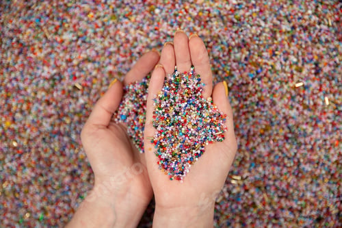 Preview: A lot of colorful beads in hands on a white background.