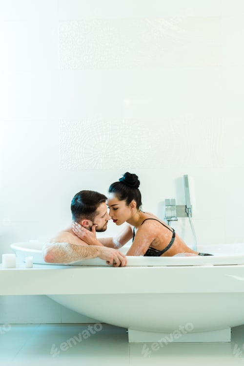 Preview: sexy brunette woman touching face of handsome boyfriend in bathtub