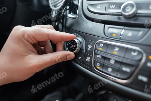 Preview: Man's hand turns the climate control wheel in a car. Temperature setting