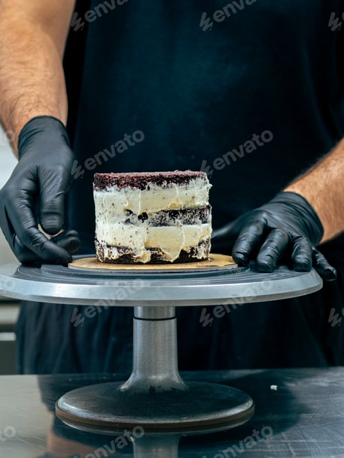 Preview: baker chef decorating cup cakes with cream and salty caramel using black gloves