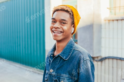 Preview: Young happy afro man listens music with headphones outdoors