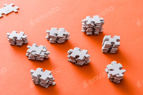 Preview: selective focus of stacked white puzzle pieces on orange