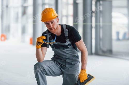 Preview: Man in grey uniform posing for a camera indoors in modern big office at daytime