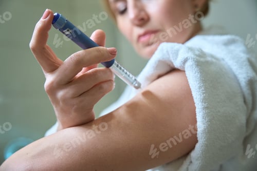 Preview: Middle-aged female gives herself an injection in the arm