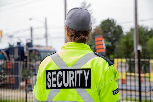 Preview: Closeup back shot of a security guard patrolling the street next to the construction area