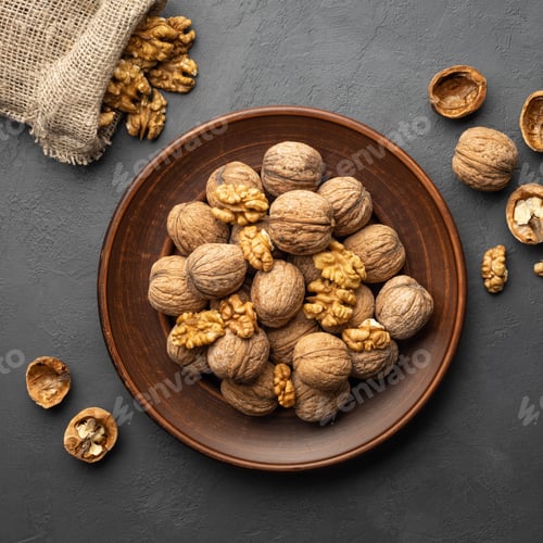 Preview: Nuts. Walnut kernels and whole walnuts on dark stone table.