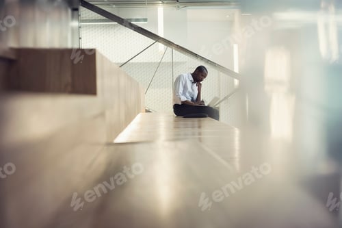 Preview: Businessman sitting on stairs using laptop