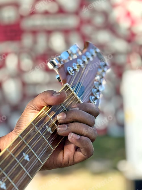 Preview: Closeup of a diverse unrecognizable guitarist musician busking in an urban park on a sunny afternoon