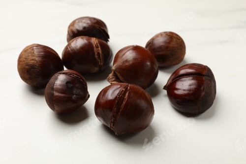 Preview: Roasted edible sweet chestnuts on white table, closeup