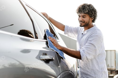 Preview: Young, smiling, Indian man washing his car with microfiber cloth