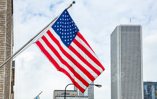 Preview: American flag in Chicago, Illinois downtown. Highrise buildings and cloudy sky background.