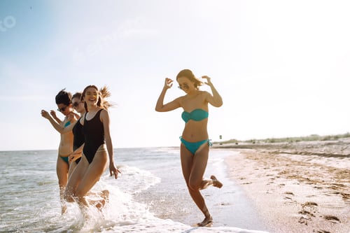 Preview: Four young girls having fun on the beach. Group of girlfriends enjoying on beach holiday.
