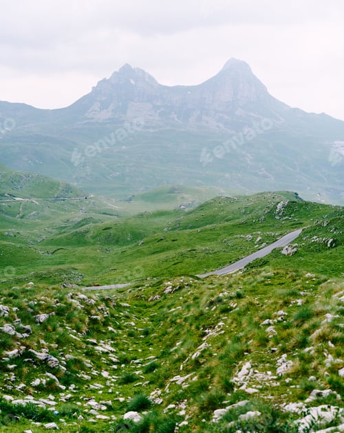 Preview: Asphalt road on a plain with mountains in the fog in the background in Durmitor National Park