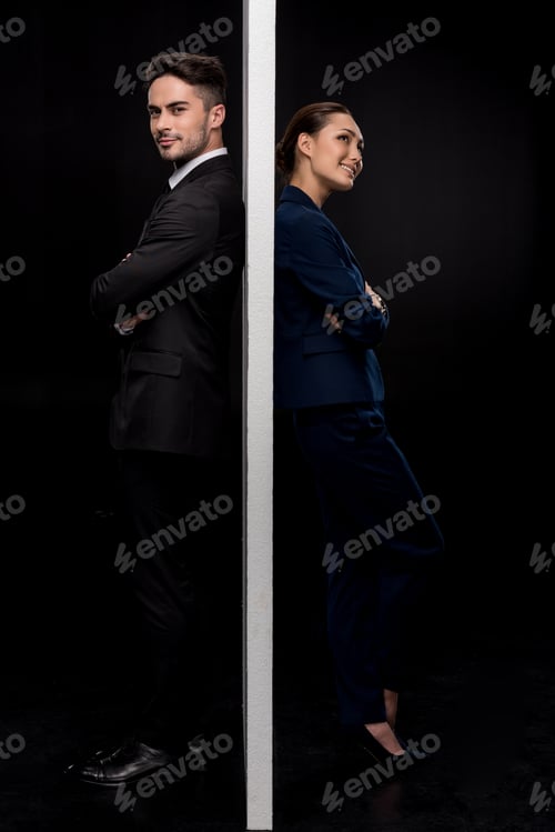 Preview: Side view of confident couple standing back to back near of separated wall isolated on black