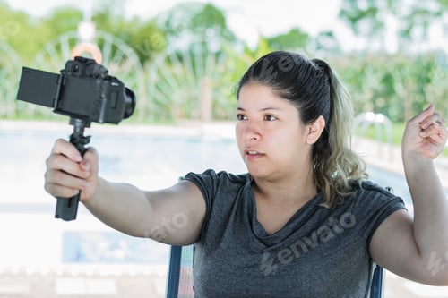 Preview: influencer woman, recording content for her social networks, with camera in hand recording herself.