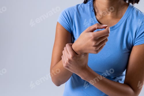 Preview: Midsection of african american mid adult woman with wrist pain against white background, copy space