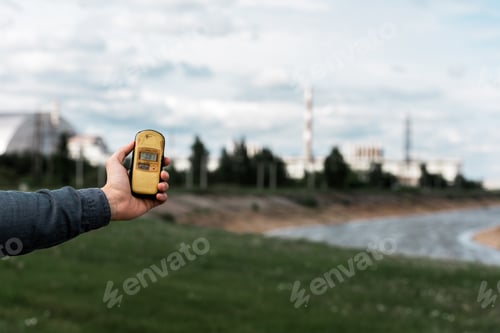Preview: PRIPYAT, UKRAINE - AUGUST 15, 2019: cropped view of man holding radiometer near chernobyl nuclear