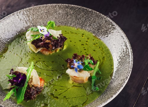 Preview: Green cream soup decorated with flowers being served in a restaurant