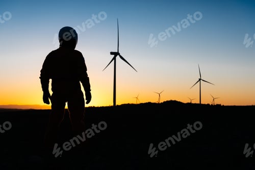 Preview: Silhouette of unrecognizable person and wind turbines in sunset