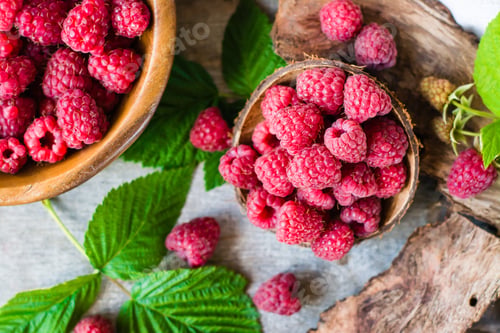 Preview: Raspberry in a bowl and in a plate, berries and leaves on a shabby wood. Top view