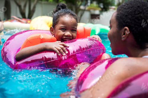 Preview: Closeup of black mother and daughter enjoying the pool with inflatable tubes
