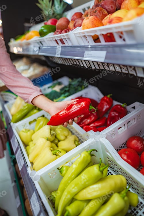Preview: Woman hand selecting fresh red pepper in supermarket