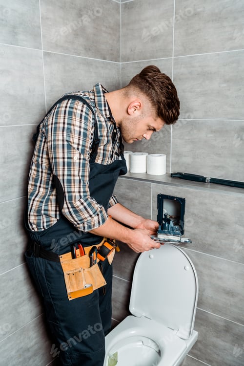 Bathroom Plumber Repairing Toilet Flush Mechanism