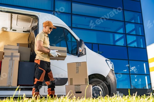 Preview: Courier in His 40s Loading Boxes Into Van Next to Modern Glassy Building