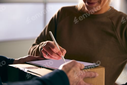 Preview: Woman Signing For Courier Delivery To Office Using Digital Tablet