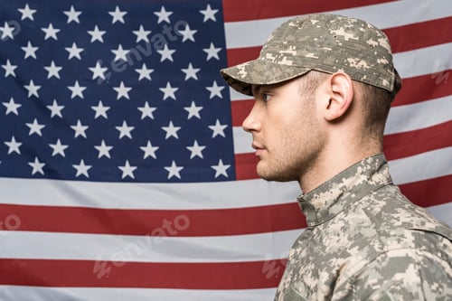 Preview: handsome man in military uniform and cap near flag of america