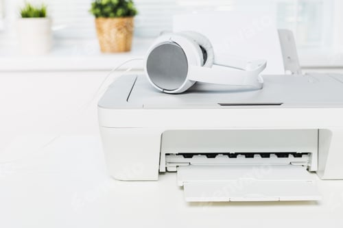 Preview: Printer and headphones on a desk in a bright workspace with plants and natural light during the day