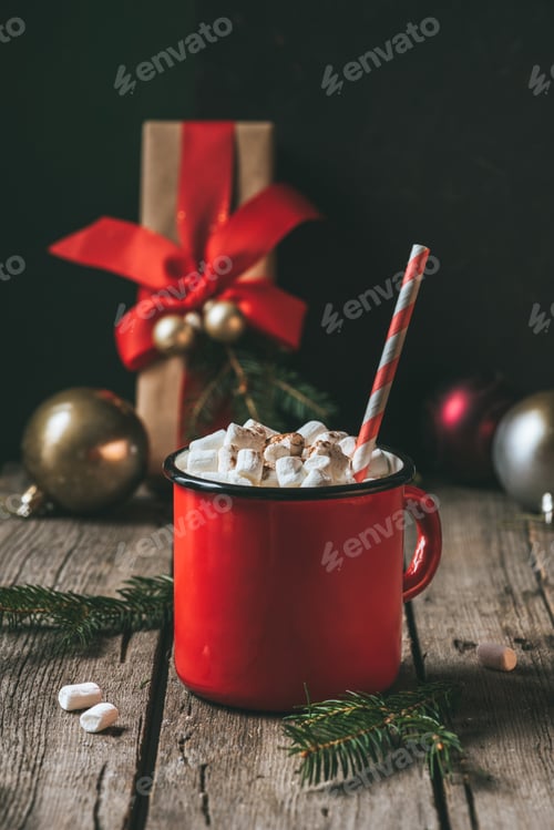 Preview: cup of hot cocoa with marshmallows on wooden table with fir tree at christmastime