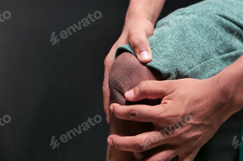 Preview: Close up on man suffering knee joint pain isolated in black