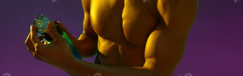 Preview: Close up of sporty man with muscled naked torso holding bottle with water on studio