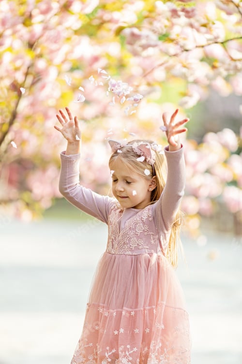 Preview: Portrait of beautiful girl with blooming flowers. Adorable little girl with sakura petals