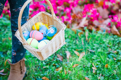 Preview: Closeup basket full of colorful Easter eggs in kids hands