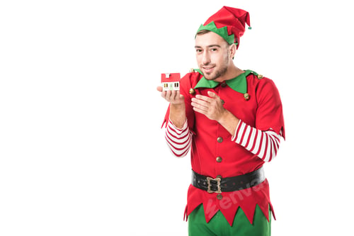 Preview: man in christmas elf costume holding house model isolated on white, real estate sale and insurance