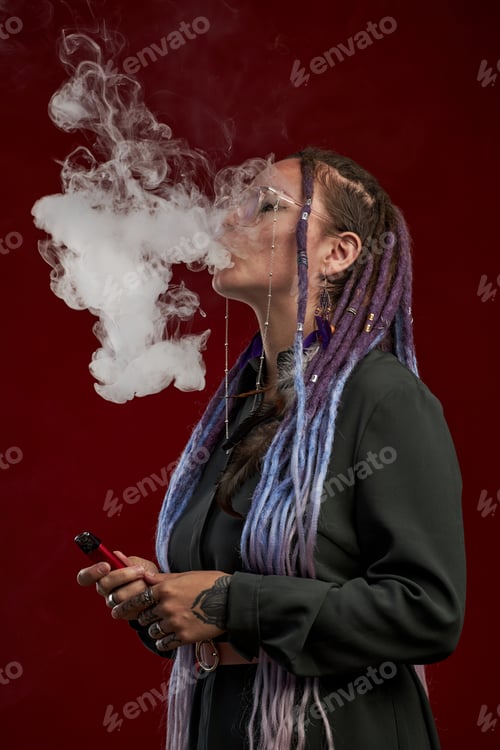 Preview: Girl with dreadlocks releasing cloud of smoke while holding vape pen