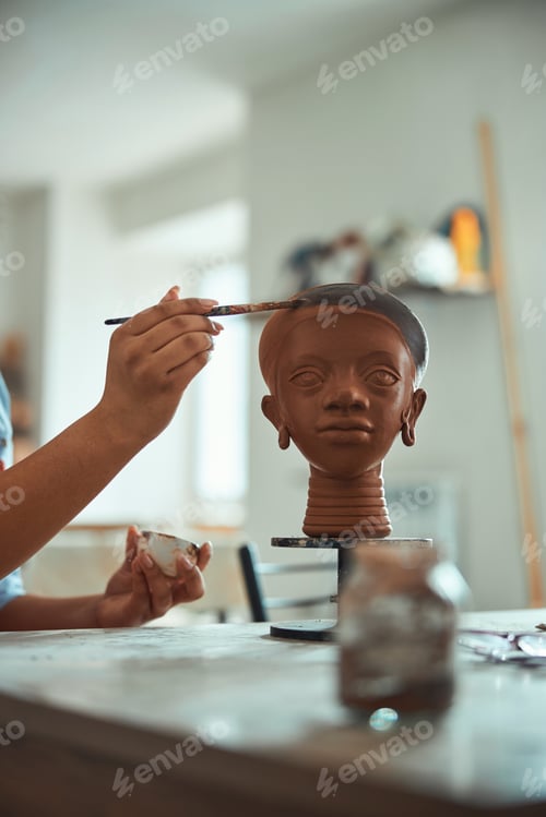 Preview: Female ceramist hand painting pottery in workshop