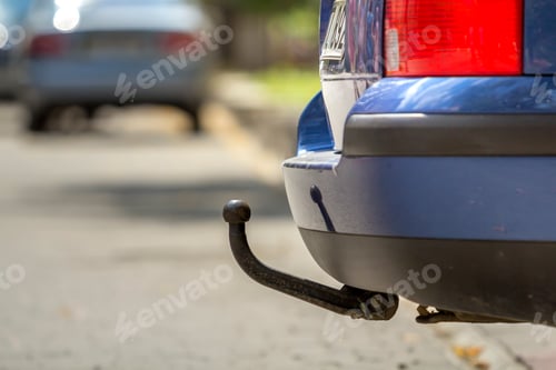 Preview: Blue car parked on sunny street, red stop lights, hook for dragging trailer, tow hitch or towbar