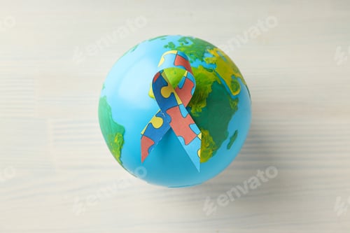 Preview: Ribbon with multi-colored puzzle pieces and a model of the planet Earth on a light background