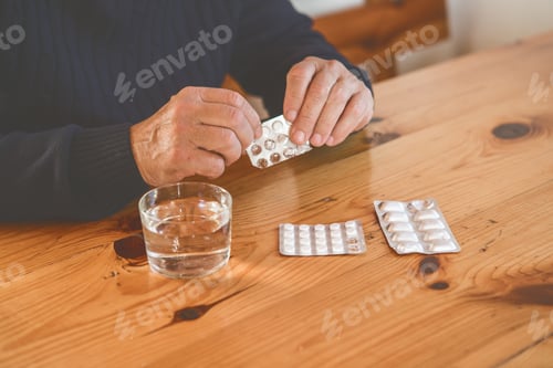 Preview: Senior man's hands picking pills with glass of water, Healthcare and medical concept