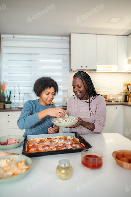 Preview: Mother and teenager making homemade pizza together in kitchen