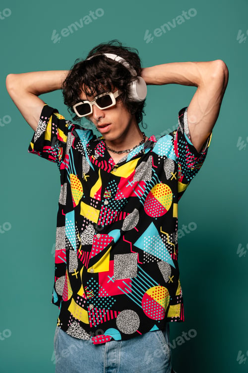 Preview: Young ethnic man with headphones enjoying music against turquoise backdrop